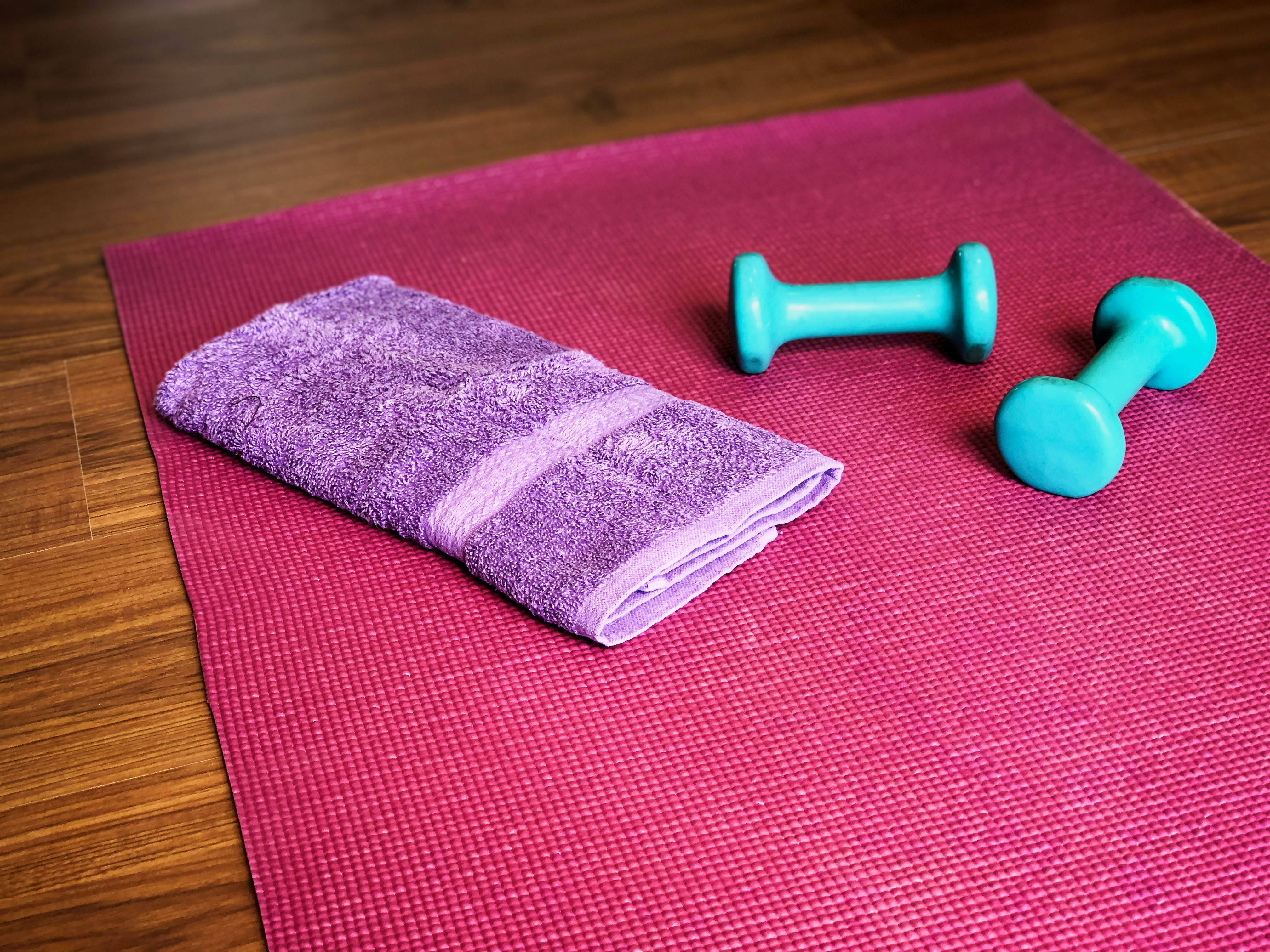 Yoga mat, towel, and light dumbbells ready for a lower-intensity home workout