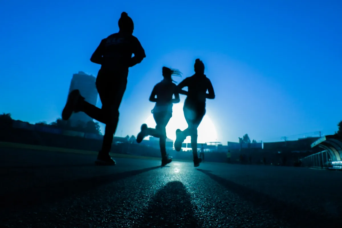 Three runners in silhouette sprinting at dawn, representing exercise as a tool for stress relief and cortisol regulation