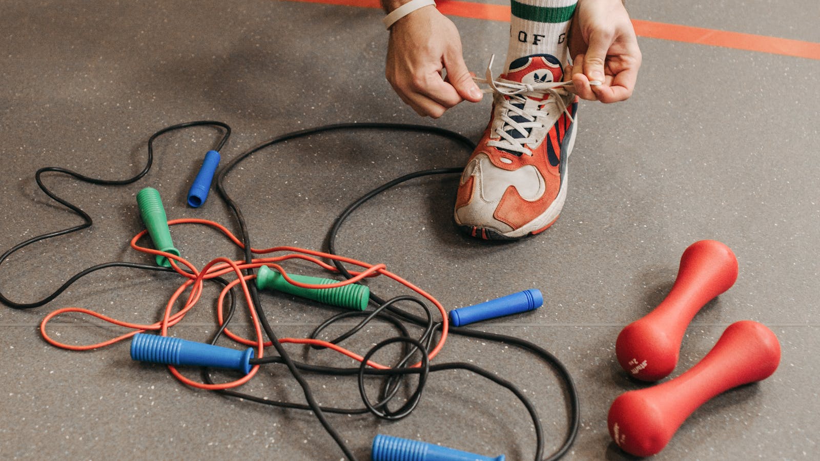Person bindet Sportschuhe vor dem Wiedereinstieg ins Training nach einer Pause