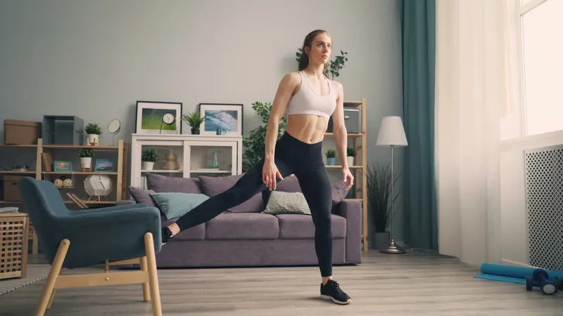 Nainen, joka suorittaa kevyen kyykkymuunnelman HIIT-kotitreenin aikana