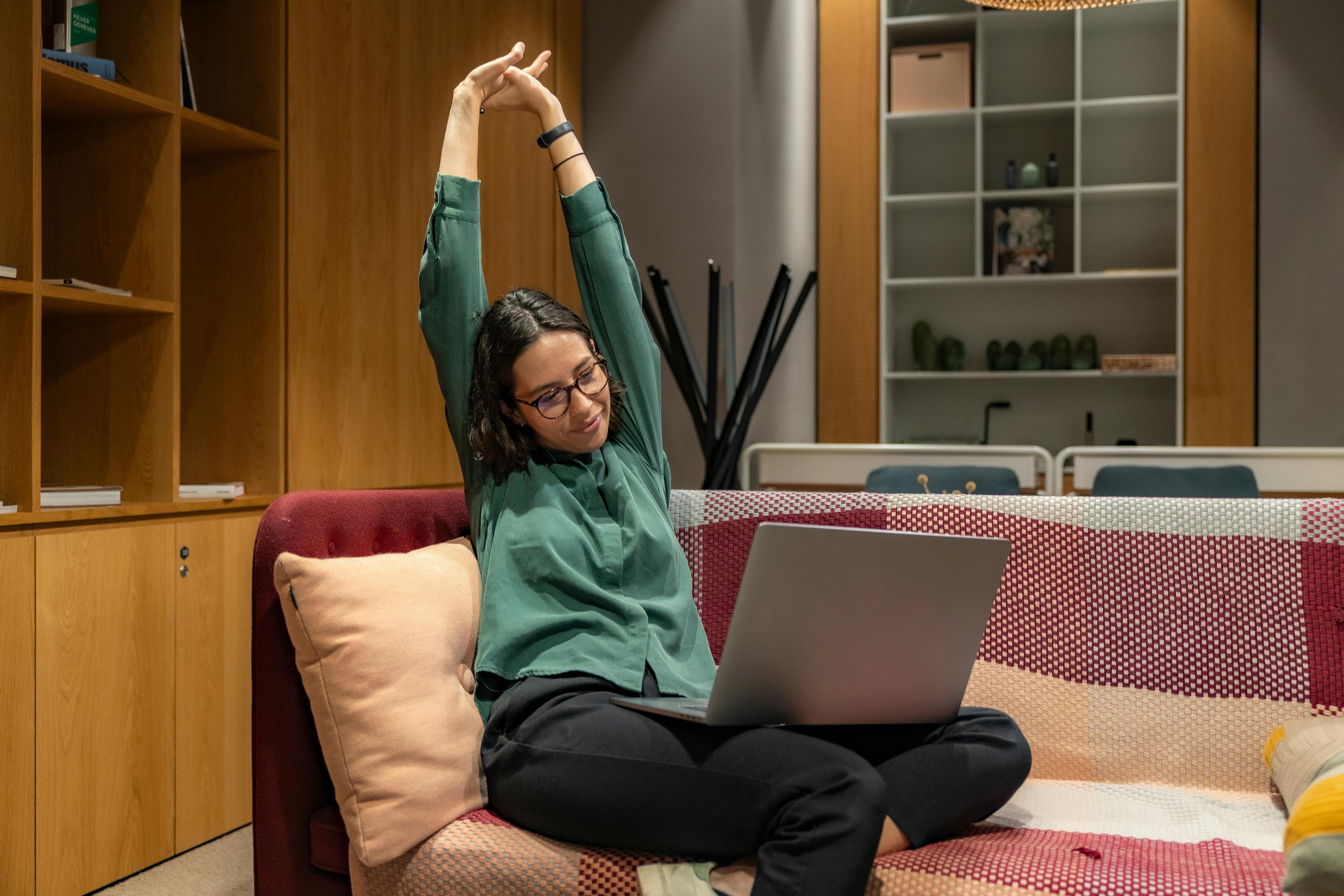 Remote Worker dehnt sich neben einem Laptop zwischen Videomeetings