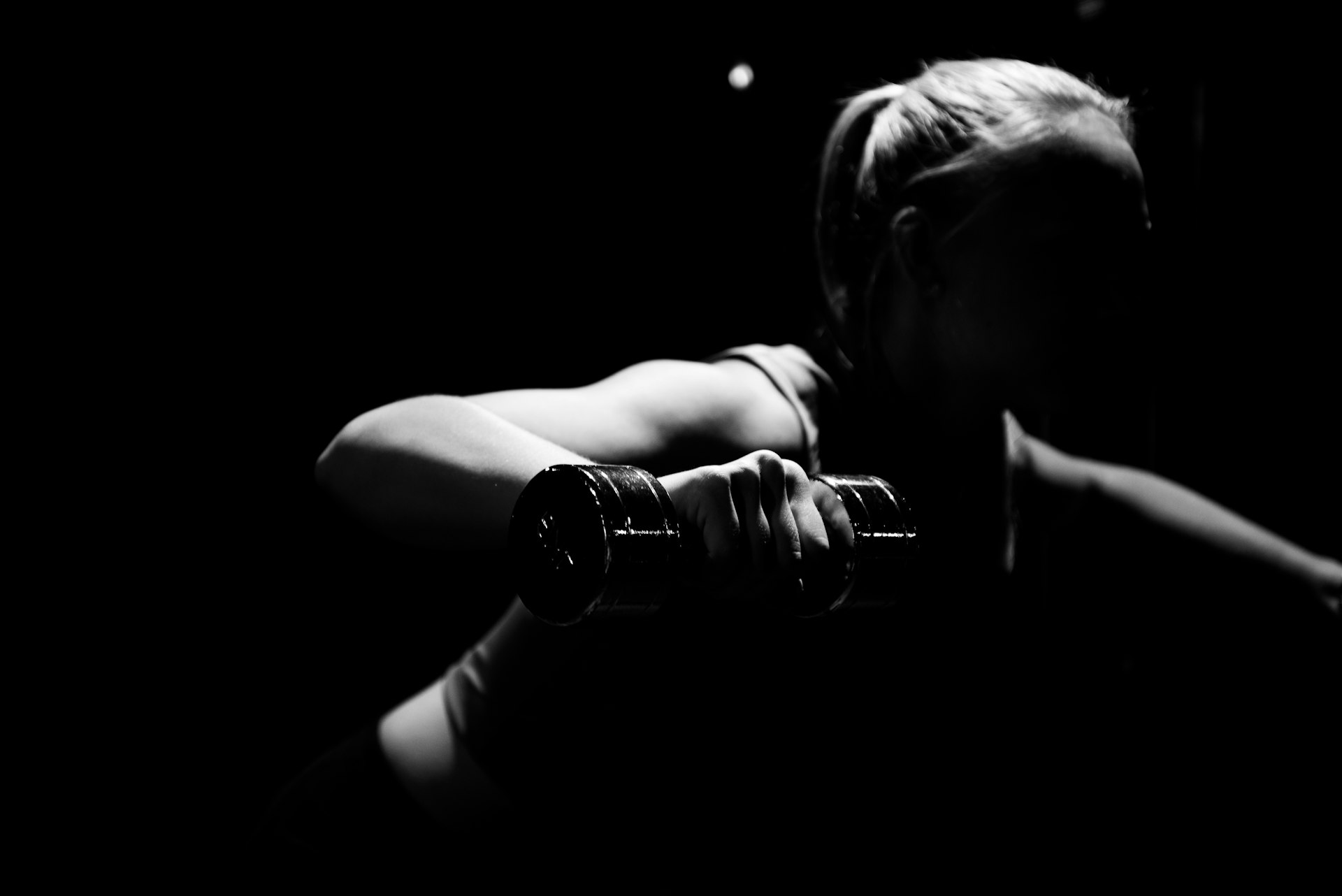 Woman holding a dumbbell during a home strength session focused on progressive overload