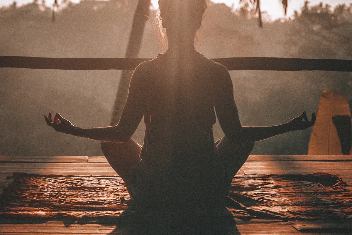 Person doing morning yoga stretch in natural light, representing travel fitness and staying active on the road