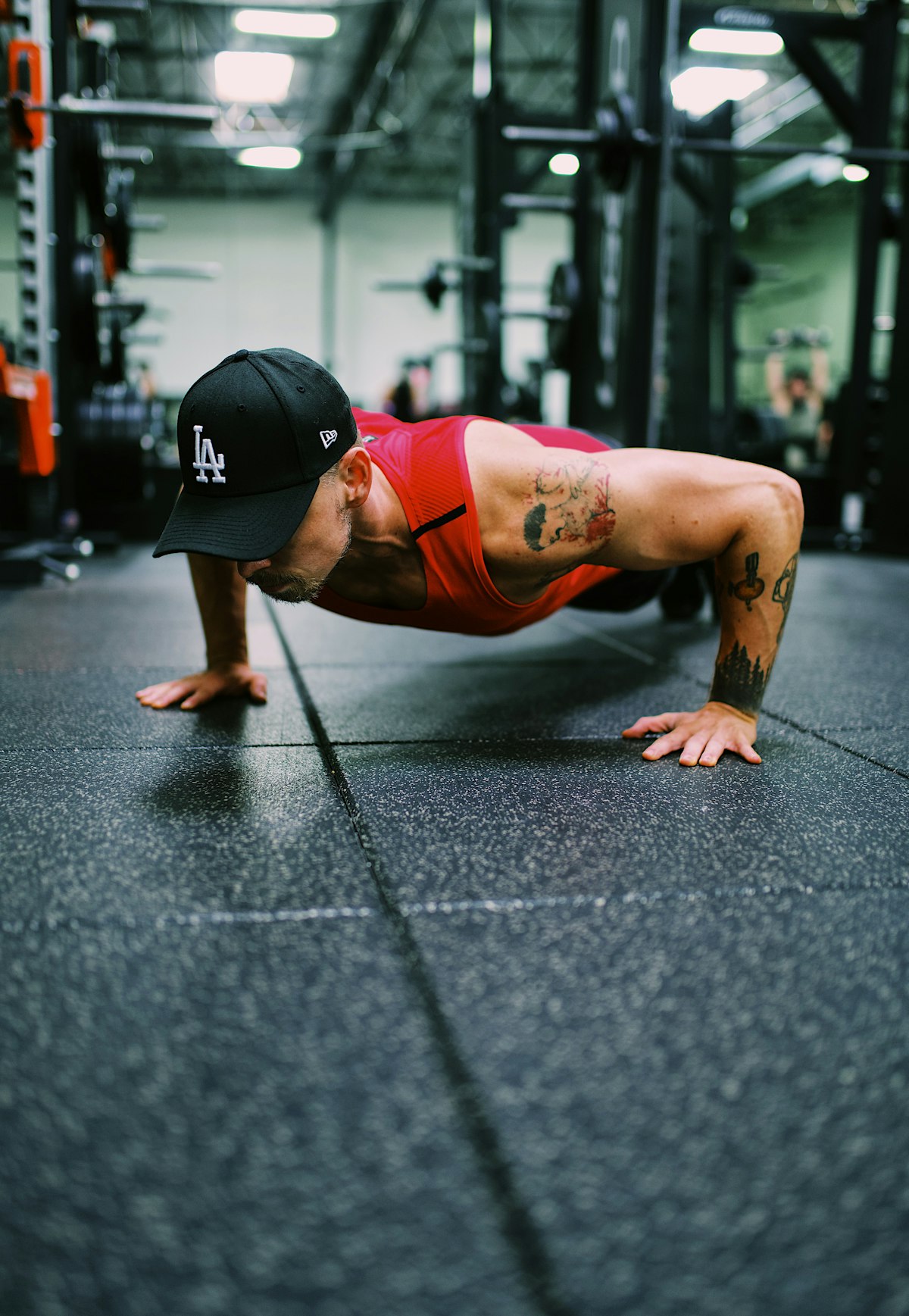 Athlete performing a diamond push-up on a gym floor, demonstrating upper body bodyweight training form