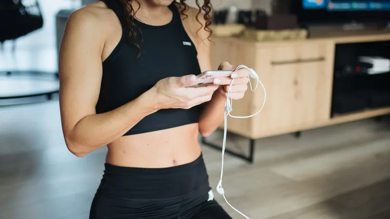 Henkilö tarkistaa fitness-sovellusta puhelimesta joogamatolla kotona