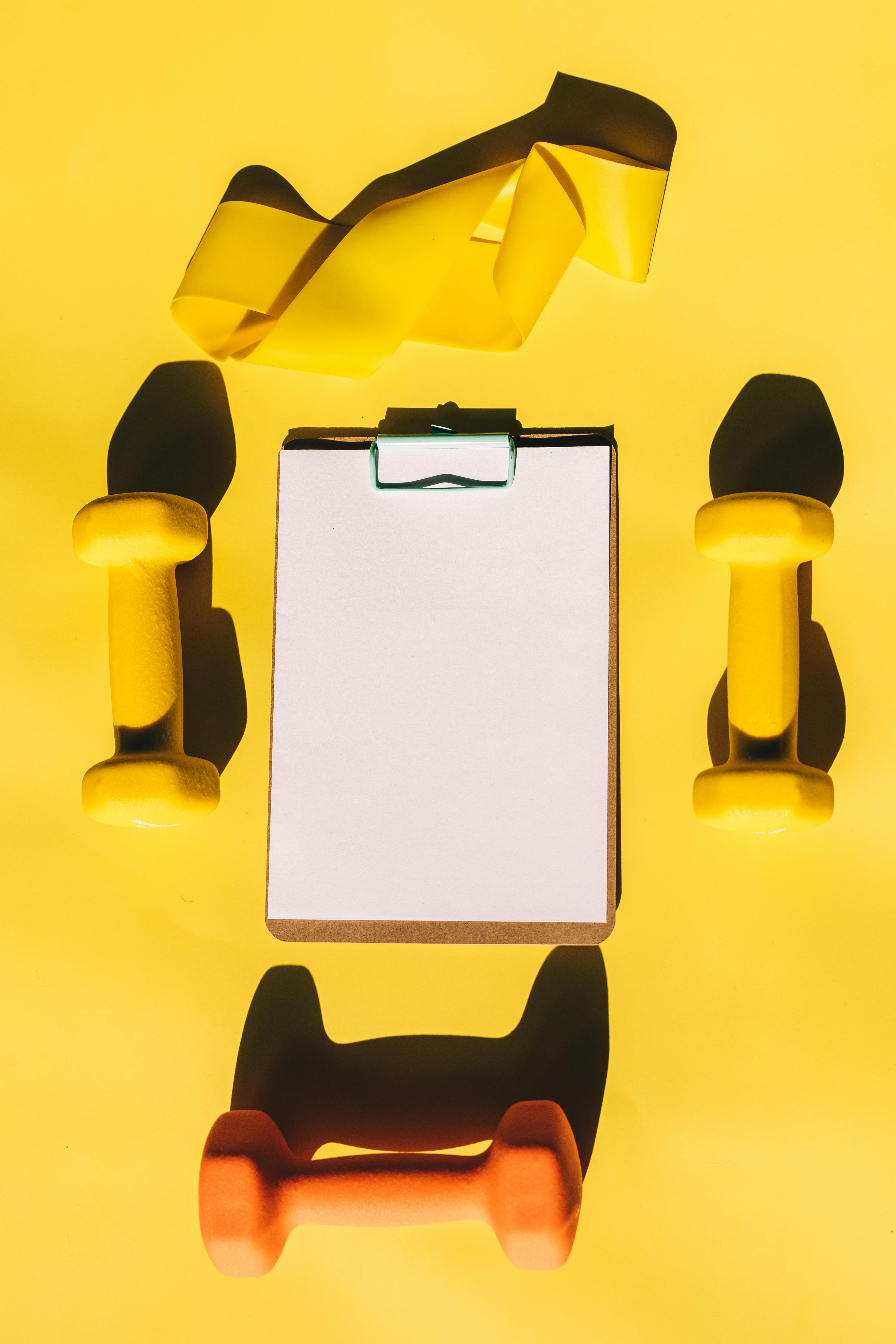 Clipboard surrounded by dumbbells and a resistance band, representing planned workout variety